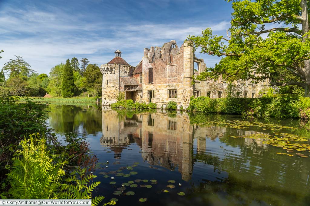 The idyllic ruins of the ancient Scotney Castle reflected across the moat on a beautiful Spring day.