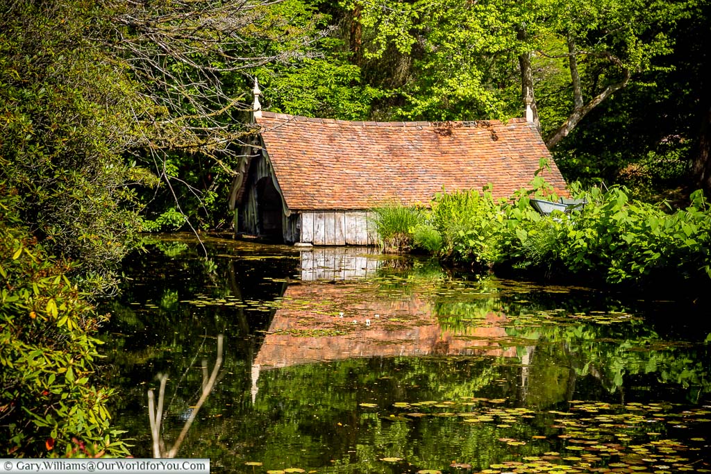 The derelict red-tilled boathouse reflected in the moat at Scotney Castle in Kent