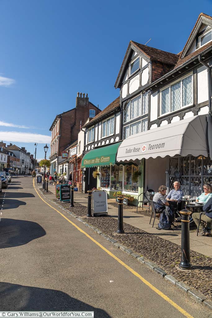 People sitting outside the Tudor Rose Tearoom, one of the many little shops that line 'The Green' in Westerham, Kent