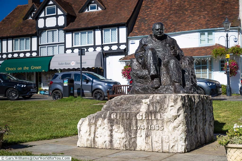 A bronze statue of a seated Winston Churchill mounted on a large piece of rock on Westerham Green in Kent