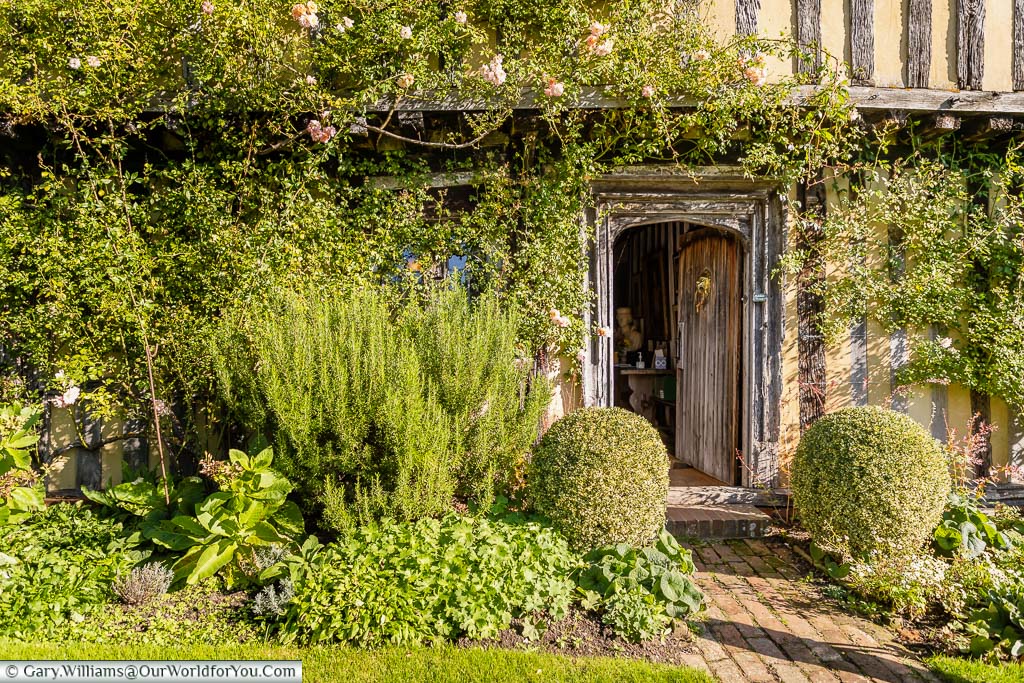 A mixed cottage garden bed surrounds the wooden front door to the 15th-century Smallhythe Place in Kent