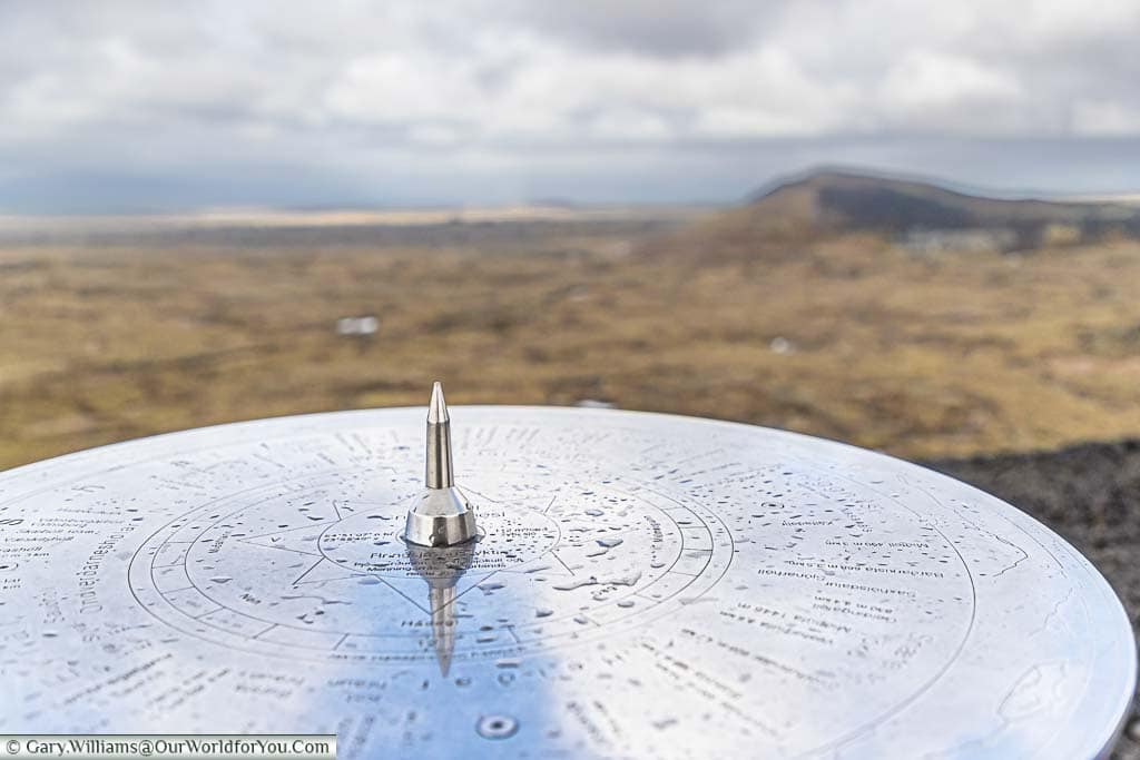 A circular stainless steel map indicating the points of interest in view in the north west icelandic landscape on top of the Saxhólar Crater.