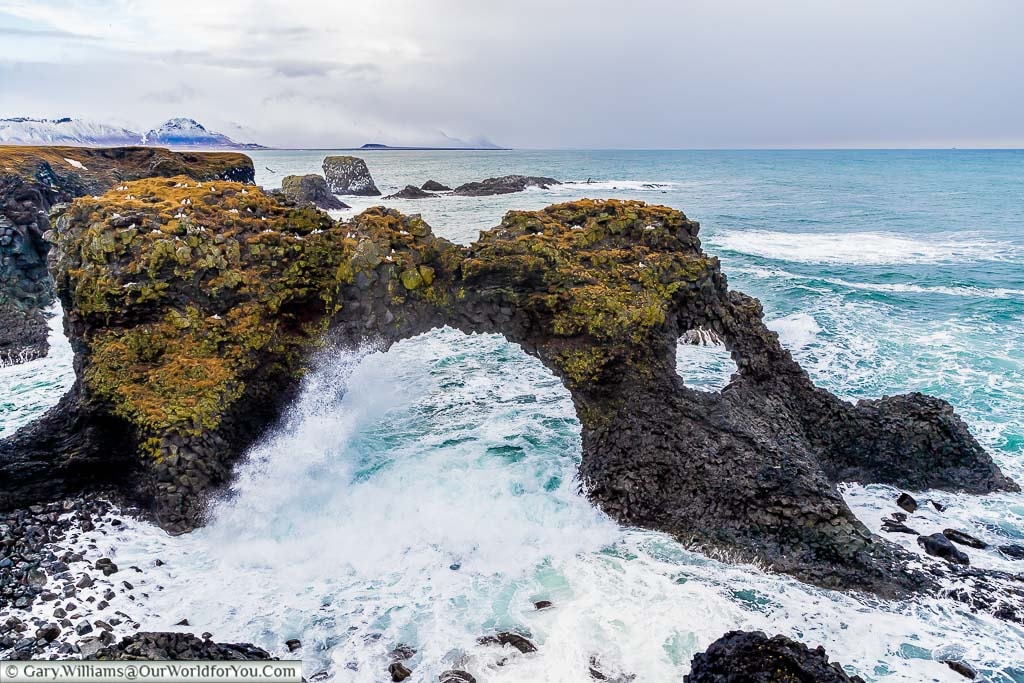 Waves crashing through a must-see sight in Western Iceland, Gatklettur, a naturally formed stone arch on the shoreline of the Snæfellsnes Peninsula
