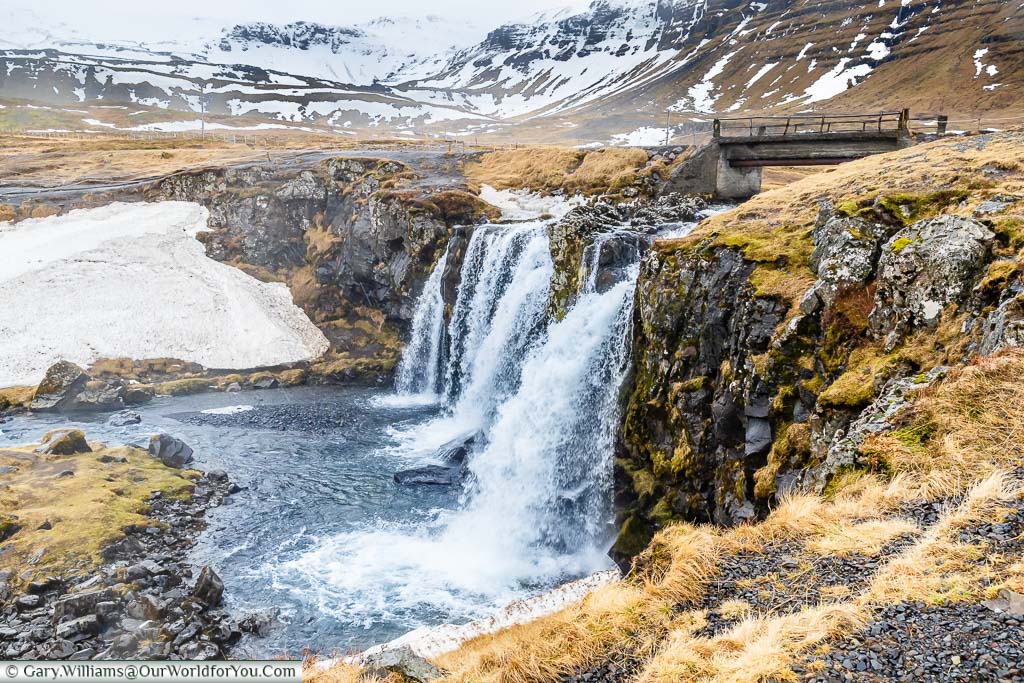 Water cascading over the Kirkjufellsfoss waterfall in the damp and dramatic landscape of northwest Iceland