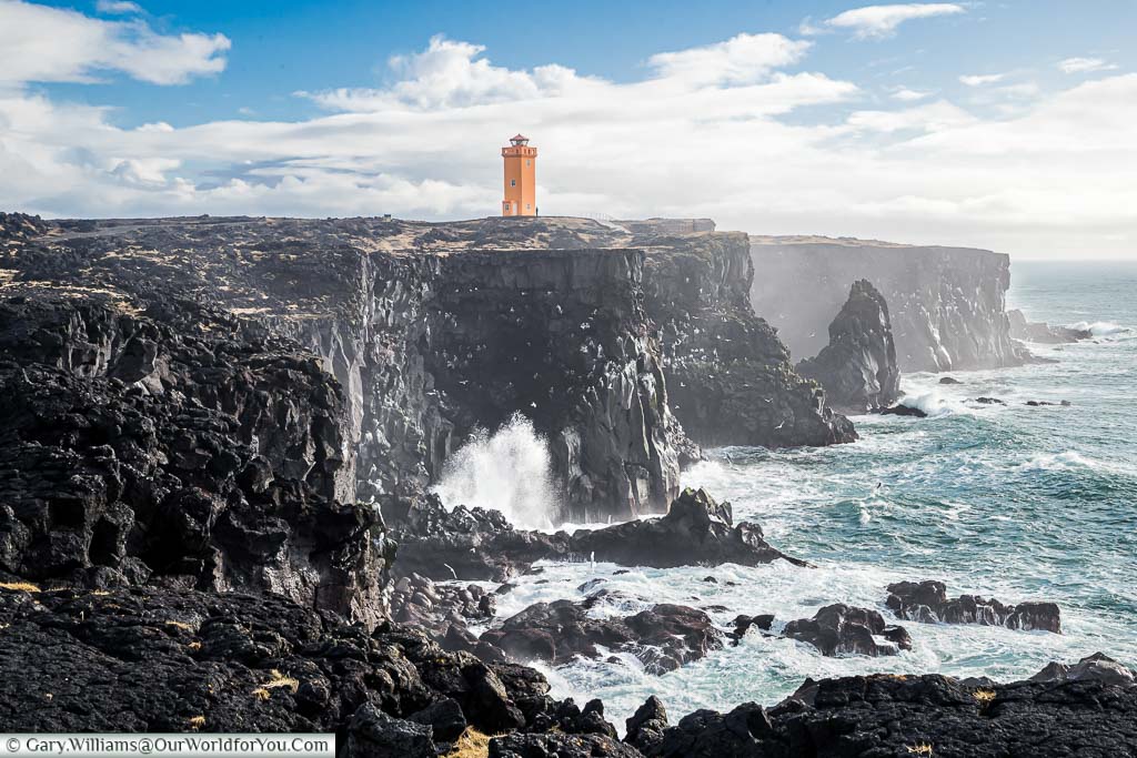 The orange Öndverðarnes lighthouse atop the jet black volcanic rock of Iceland's north west peninsula