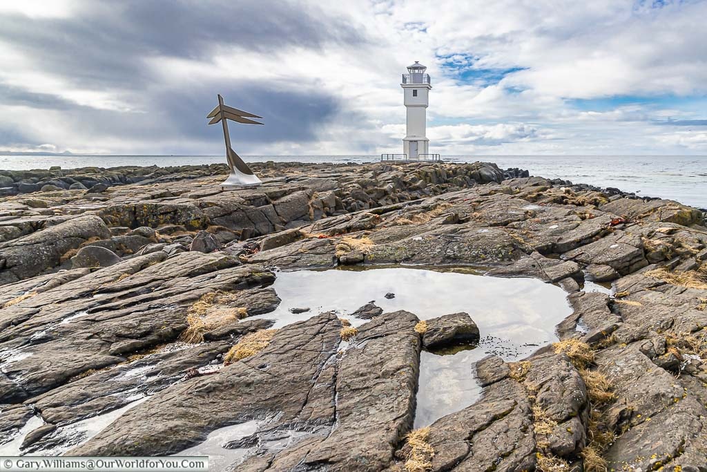A lighthouse perched at the end of a rock outcrop in Akranes in Western Iceland