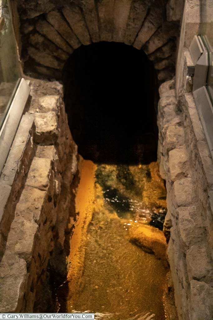 A preserved Romain drain filtering the warm spring water within the museum in the Roman Baths