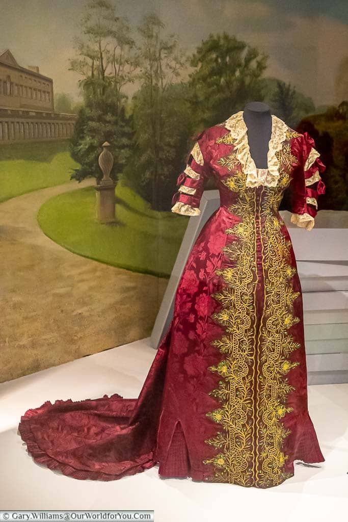 A Georgian red gown with a train and gold trim in the Fashion museum in Bath
