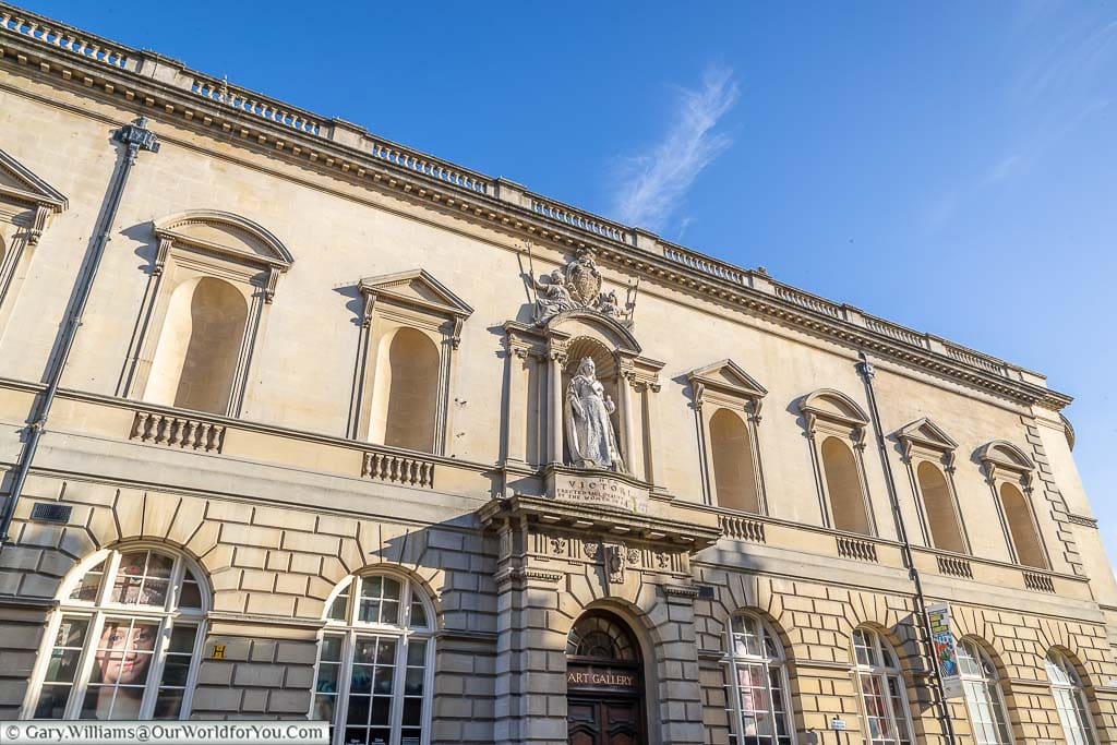 The exterior of the Victoria Art Gallery in Bath lit by golden sunlight under deep blue sky