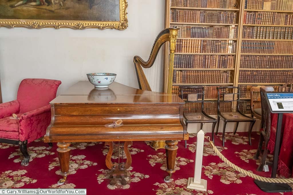 A mahogany veneered baby grand piano and harpsichord in the south gallery of Lacock Abbey in Wiltshire.