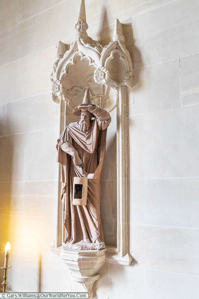 A stone statue of a wizard holding a lantern in the grand hall of Lacock Abbey