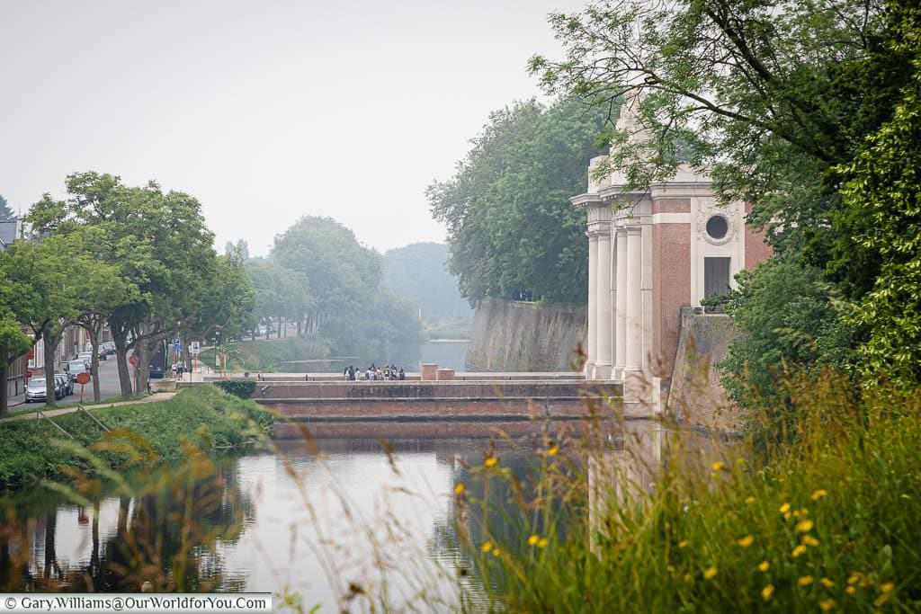 A view along the ramparts of Ypres with a moat in front and the Menin Gate.