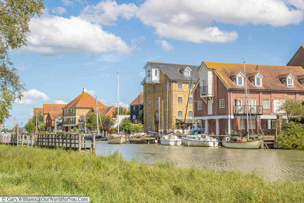 Boats moored up alongside converted warehouses on Faversham Creek in a picturesque town in Kent