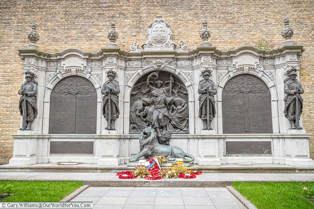 The ornate Ypres War Victims Memorial carved of stone with brass inlays and brass statues of soldiers and a lion resting at their feet