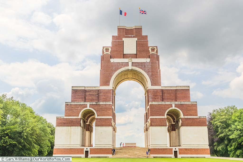 The 43-metre high Thiepval Memorial, built of red brick and cream-coloured stone, with both the French & British flags fluttering in the breeze.