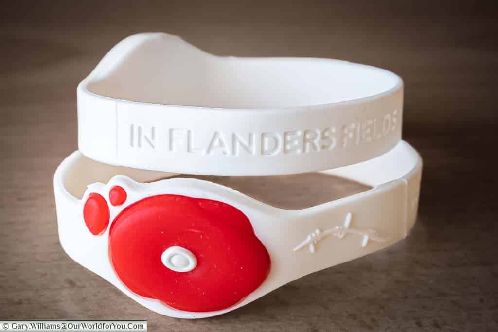 In Flanders Field Museum white wristband embelished with a red poppy, and the phrase 'In Flanders Field'
