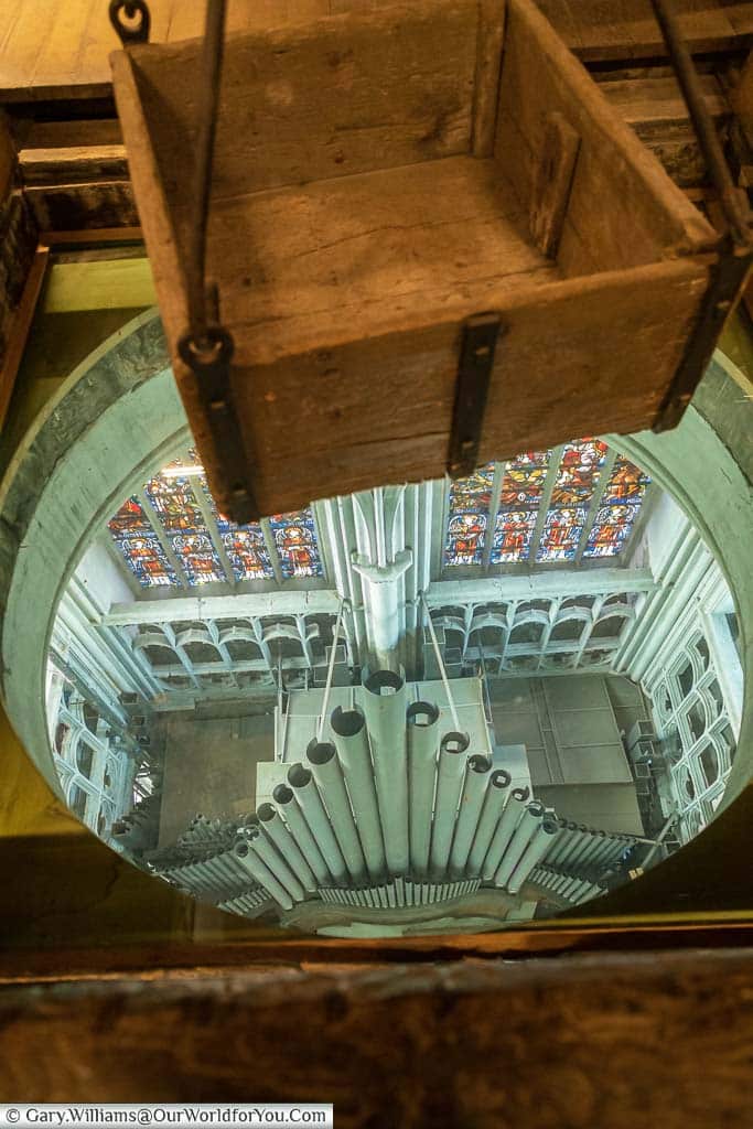 The view down from the crane chamber to the pipes of St Rumbold's Cathedral's organ below and the stained glass window behind.