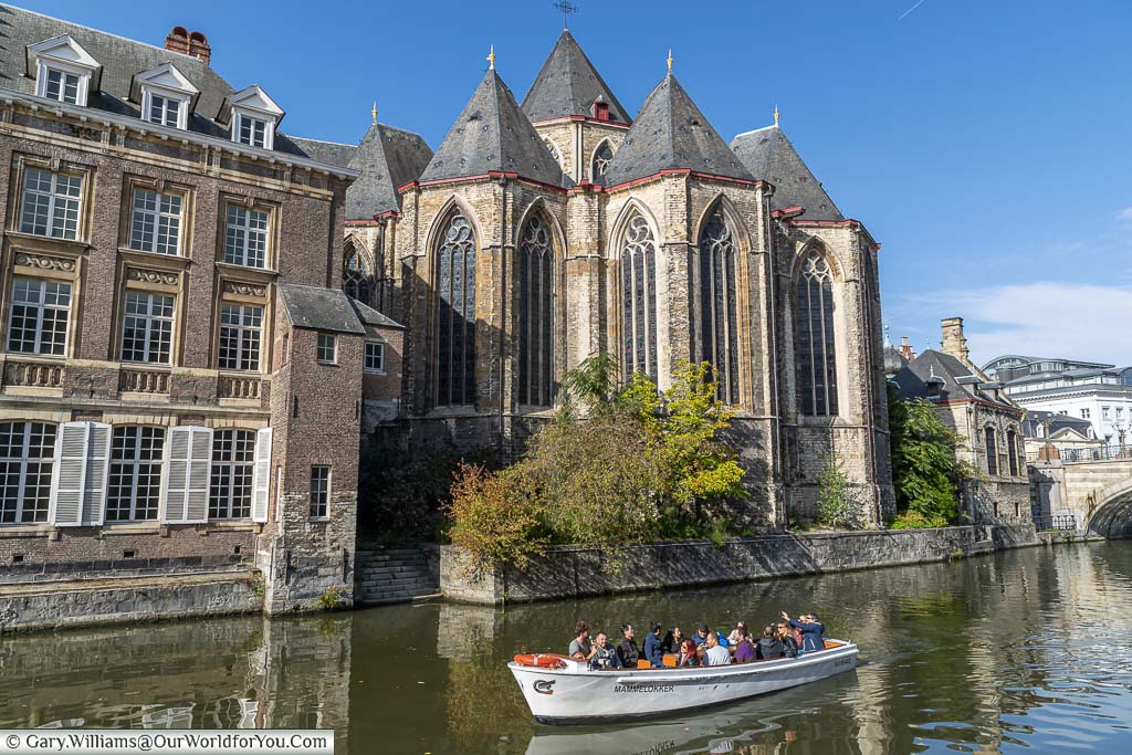 A sightseeing boat in front of Saint Michael's Church on the river Leie in Ghent.