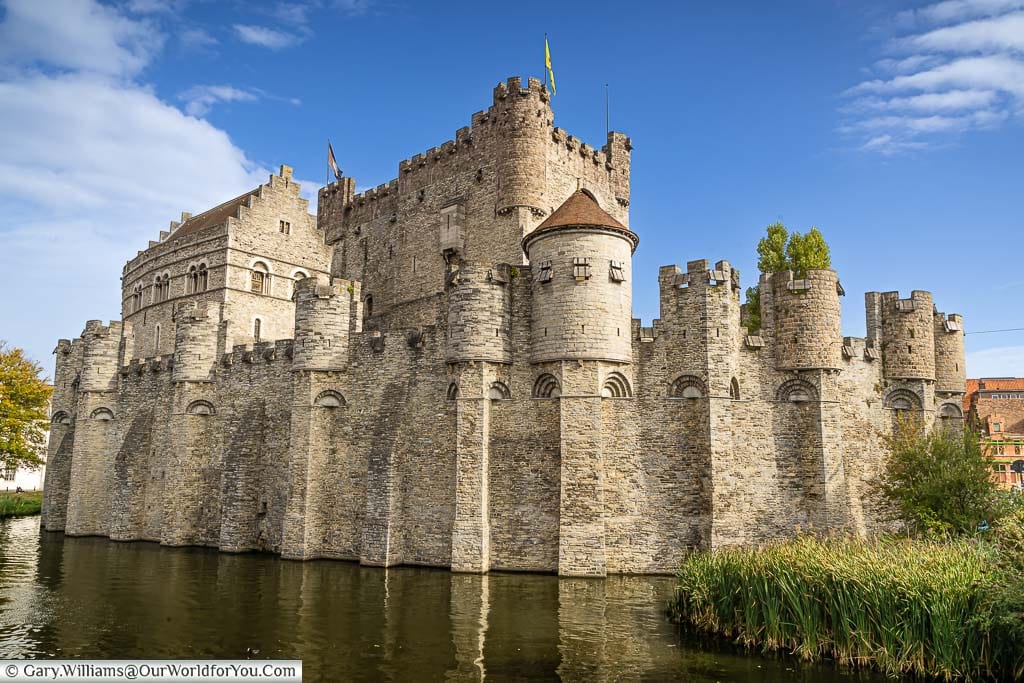 The Gravensteen stone medieval castle is a must-see in Ghent, Belgium. This view is of the water in front of the castle walls with the keep in the centre.