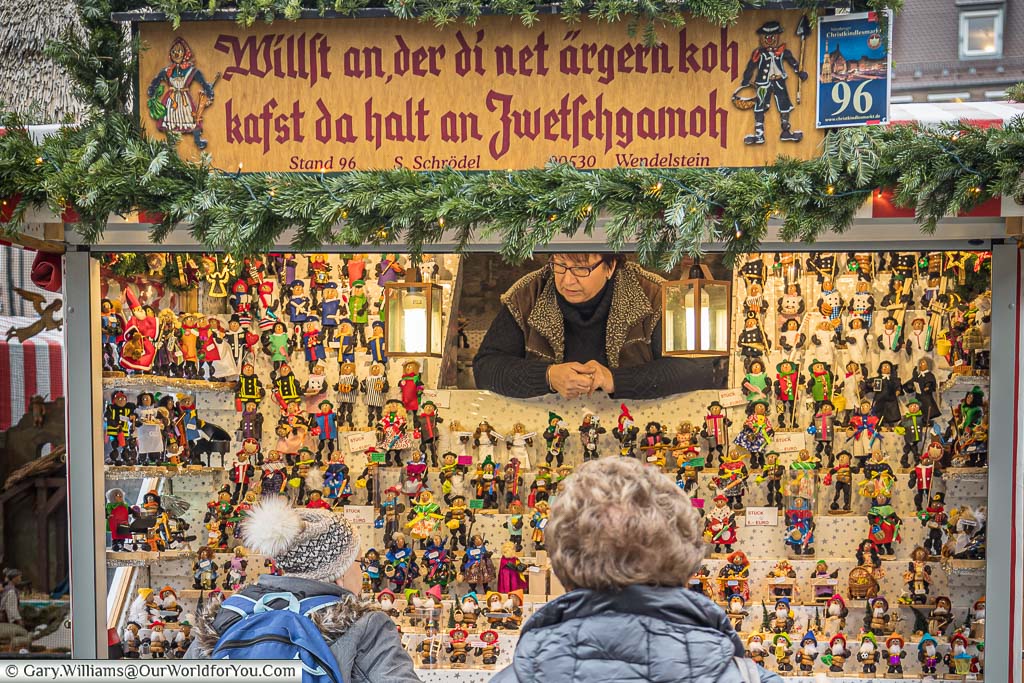 A woman selling hand crafted Zwetschgenmannle, prune men, as christmas decorations on a nuremberg christmas market in germany