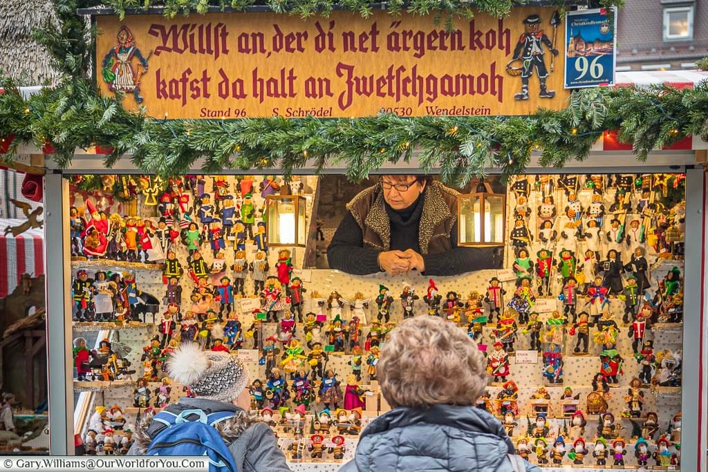 A woman selling hand crafted Zwetschgenmannle, prune men, as christmas decorations on a nuremberg christmas market in germany