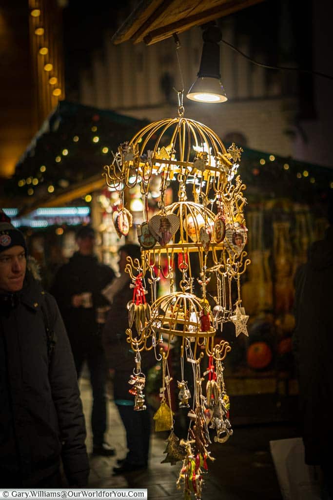 A hanger from a stall in Munich's Christmas market lit with a spotlight catch the decorations hanging from it.