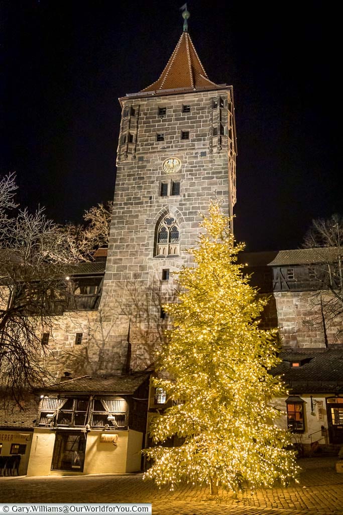 A seven-metre Christmas tree, lit with golden fairy lights, stands in front of a stone tower of Nuremberg's Castle