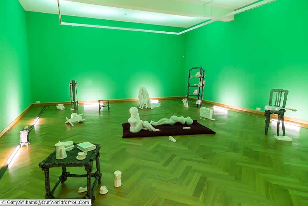 A collection of white plaster exhibits in a room illuminated in green in the Contemporary art section of the ‘M’ Leuven gallery in leuven.