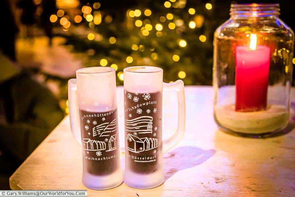 Two frosted glasses of Gluhwein, next to a candle lantern, on an outside table in the Schadowplatz market in Düsseldorf