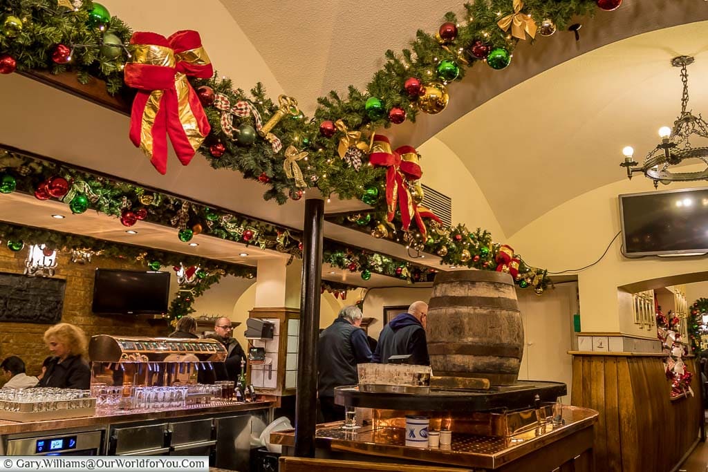 Inside the Brauerei zum Schlüssel, in düsseldorf, decorated for christmas, with its wooden beer barrel taking centre stage behind a horseshoe-shaped bar.
