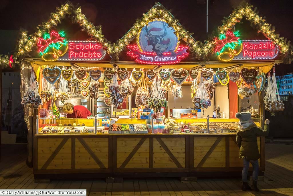 A young girl, a lone customer at a christmas market stall, picking her favourite gingerbread tree hanger in düsseldorf, germany