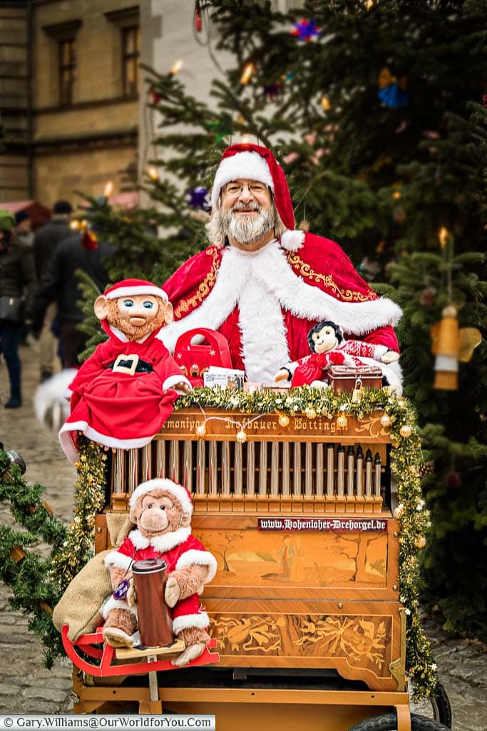 Santa playing a traditional street organ with a stuffed monkey as his collection assistant.