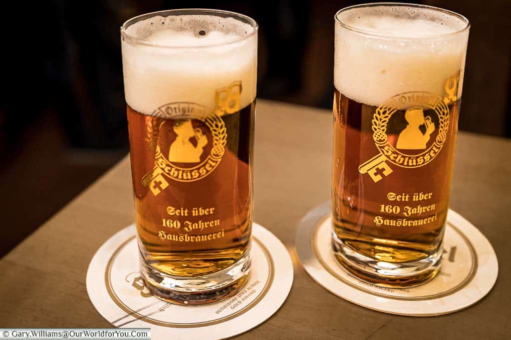Two small glasses of Schlüssel Alt Beer on beer mats bearing two pencil marks in a bar in düsseldorf, germany