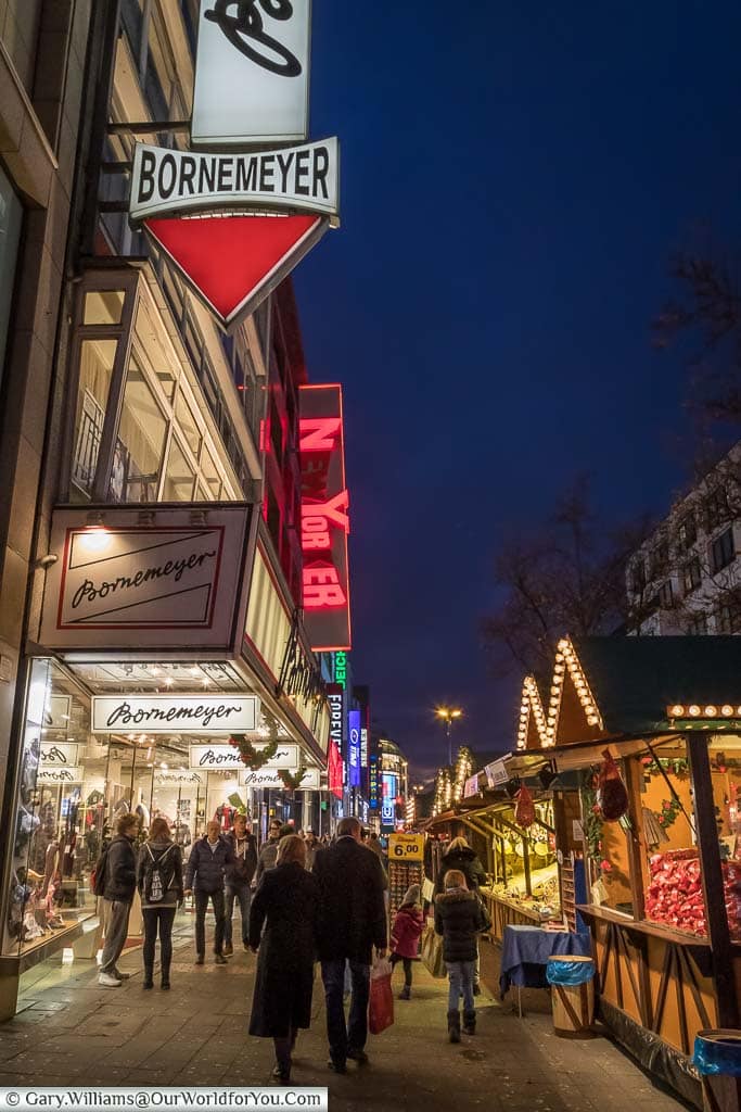 A street scene of people walking past christmas market stalls that line one side of Schadowstrasse in düsseldorf, germany