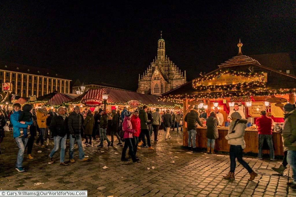 The view from the edge of the main christmas market in nurmberg overlooking the decorated wooden huts with the Frauenkirche in the background.