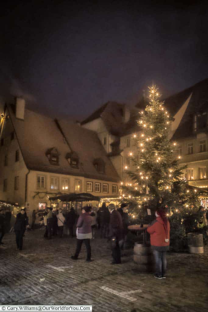 An illuminated christmas tree in the centre of a small christmas market in rothenburg ob der tauber at night.
