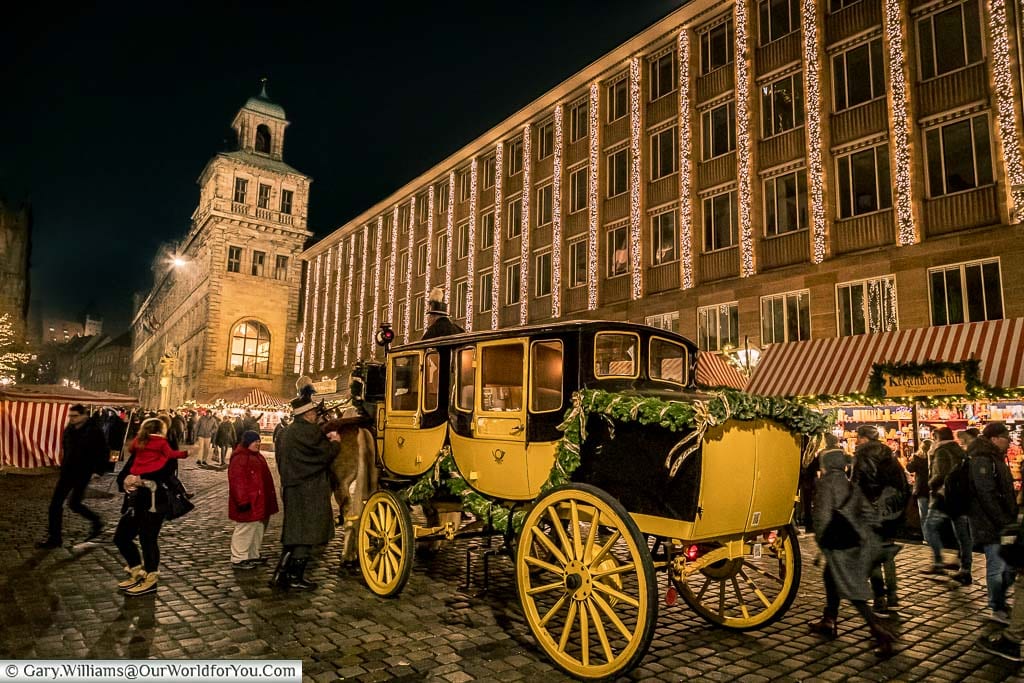 A yellow and black horsedrawn carriage, decorated for Christmas, on the streets of Nuremburg in the late evening