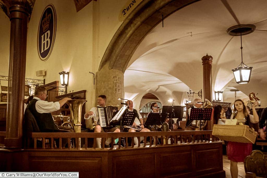The Oom-pah band in their section of the Hofbrauhaus in Munich, with a pretzel seller her wares to the patrons.