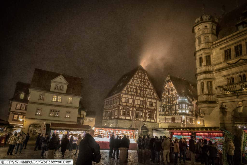 The main christmas market in rothenburg ob der tauber's marktplatz under a misty december night sky