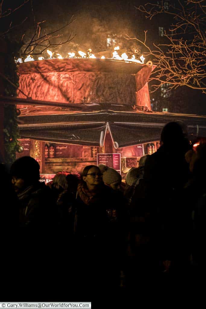 Flames around the edge of a giant beaten copper punchbowl full of gluhwein above a christmas market stall in nuremberg