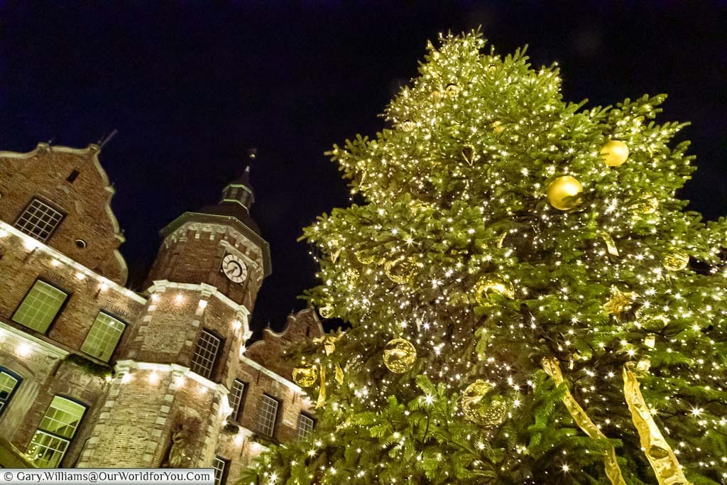 Looking up at a christmas tree decorated with golden baubles, ribbons and twinkling lights in front of the rathaus in düsseldorf at night