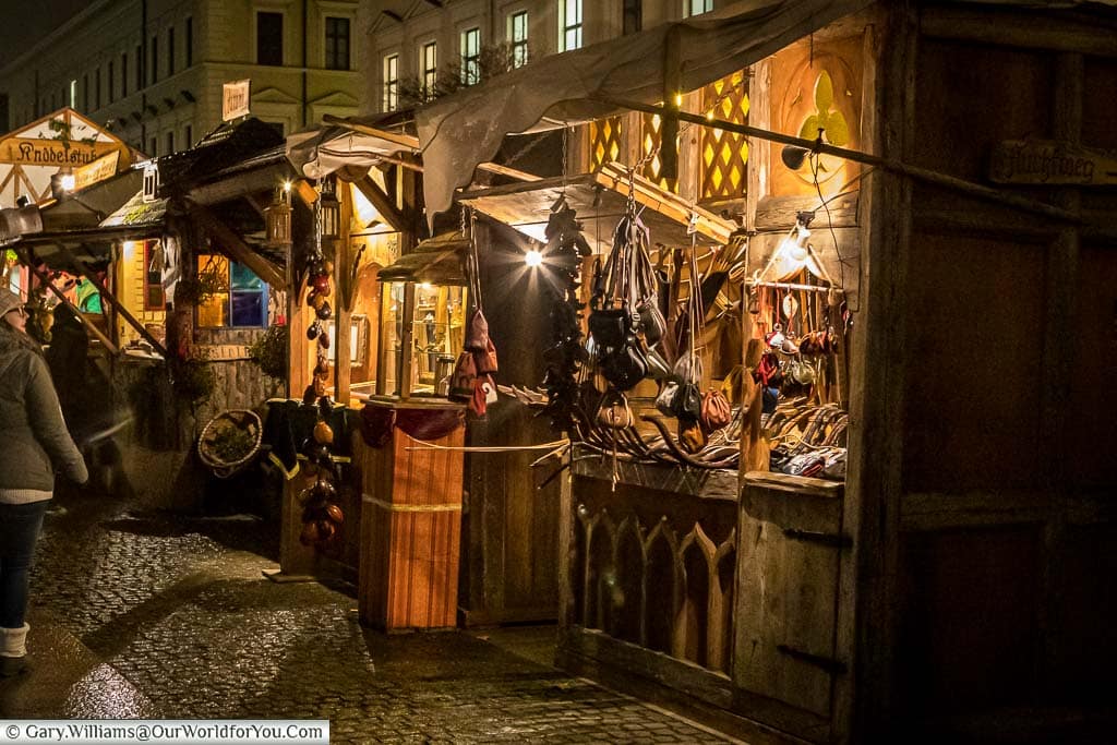 A collection of wooden stalls in the Medieval Christmas market selling artisan craft products such as bags and jewellery.