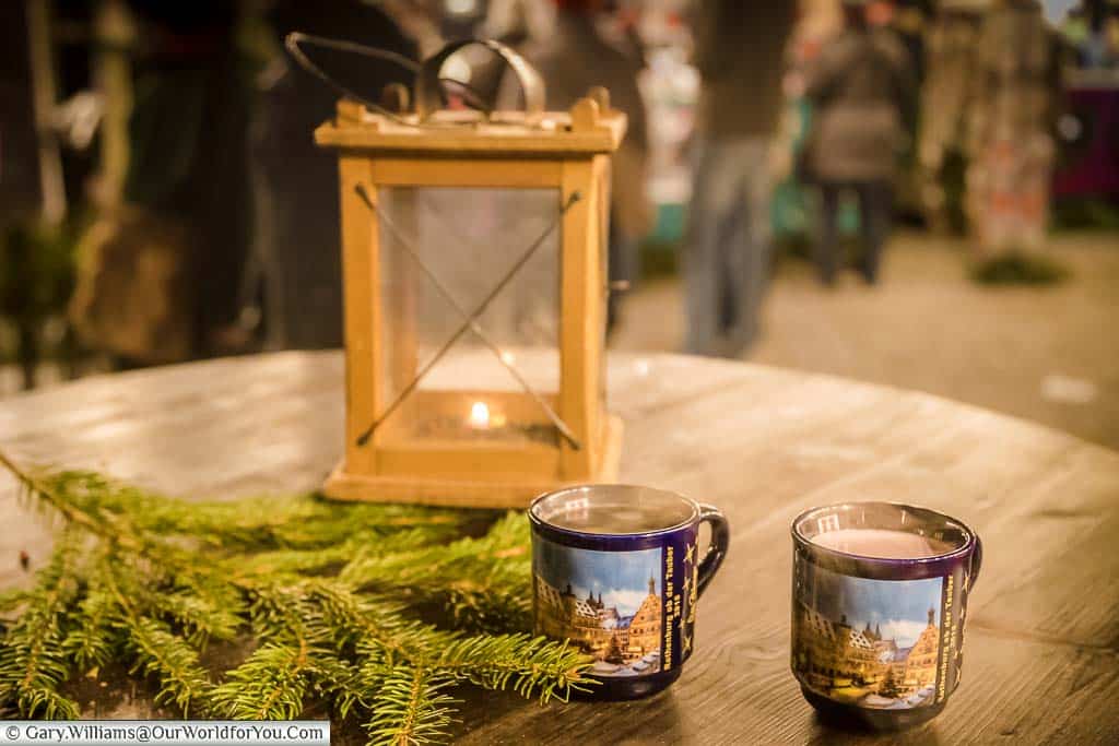 Two mugs of steaming glühwein in front of a lantern in Rothenburg ob der Tauber's Christmas Markets, Germany