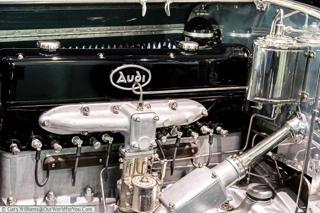 A closeup of a vintage Audi engine with a gloss black block contrasted against silver streel components in the Audi Museum in Ingolstadt, Germany