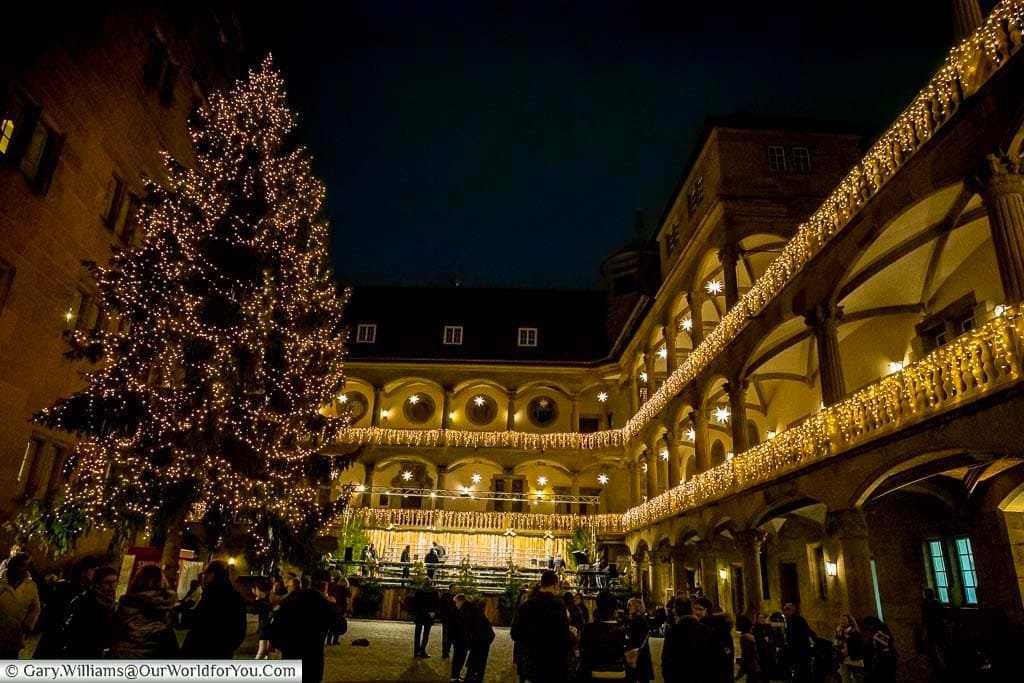 Inside Alten Schloss in stuttgart at night with its decorated Christmas Tree and twinkling balconies.