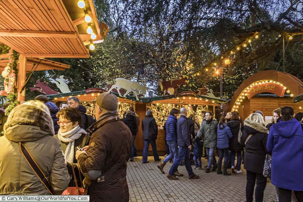 Groups of people gathering around huts in the Stadtgarten Christmas market