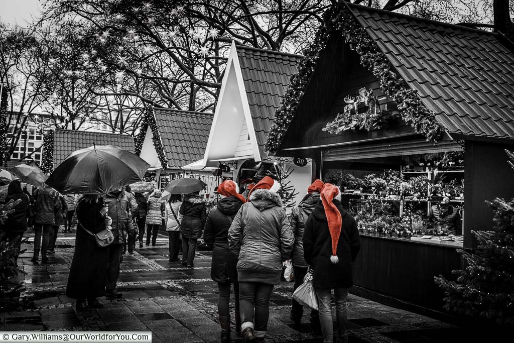 A selective coloured black and white shot of the angel christmas market in cologne with a group of ladies wearing red santa hats
