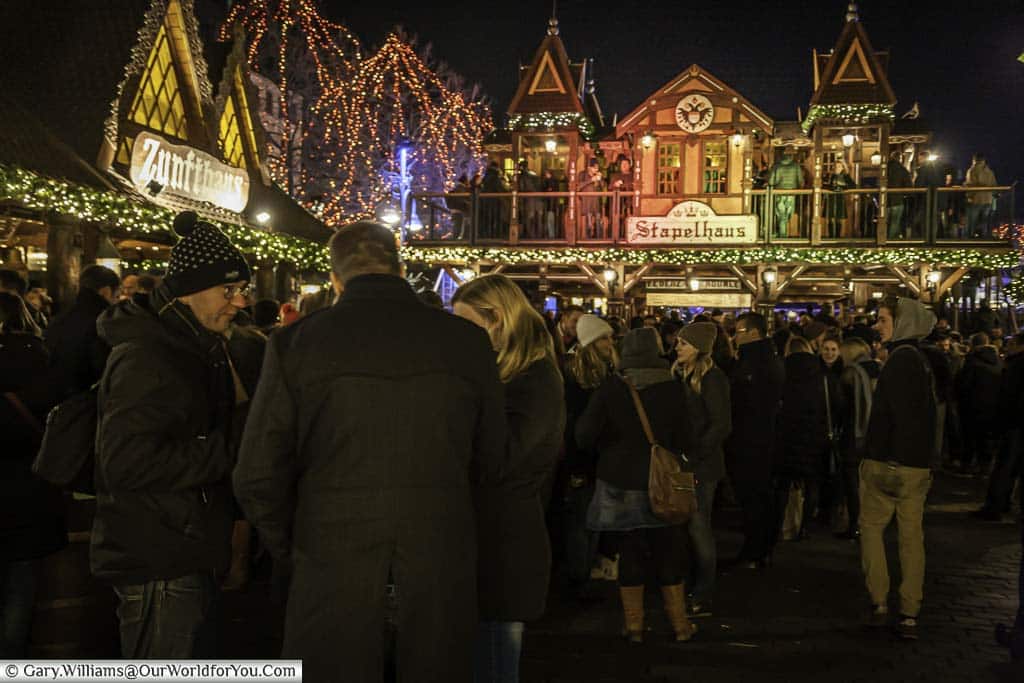Crowds in front of the Christmas huts, including the double-storey Stapelhaus, in the Elves market in Cologne after dark.