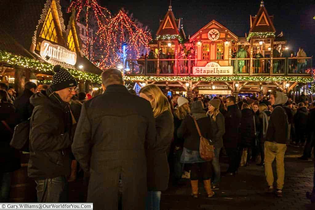 Crowds in front of the Christmas huts, including the double-storey Stapelhaus, in the Elves market in Cologne after dark.