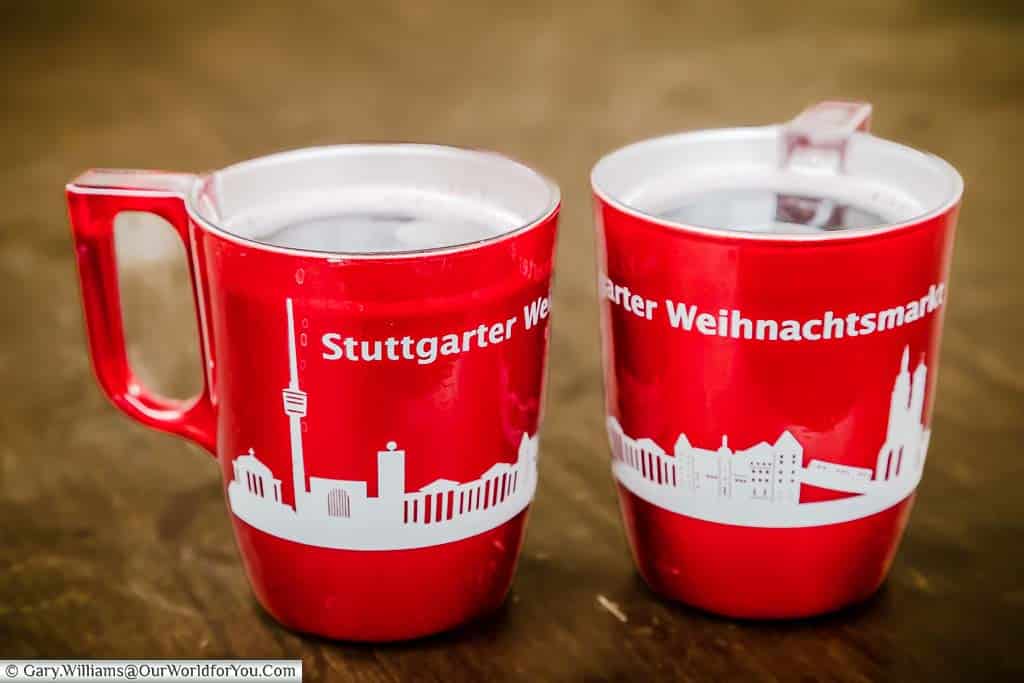 Two bright red plastic mugs of glühwein with Stuttgart's Christmas Market